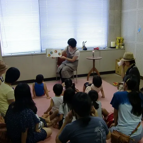 公式の今回案内に掲載されたおはなし会で読み聞かせをしている写真（紹介写真）