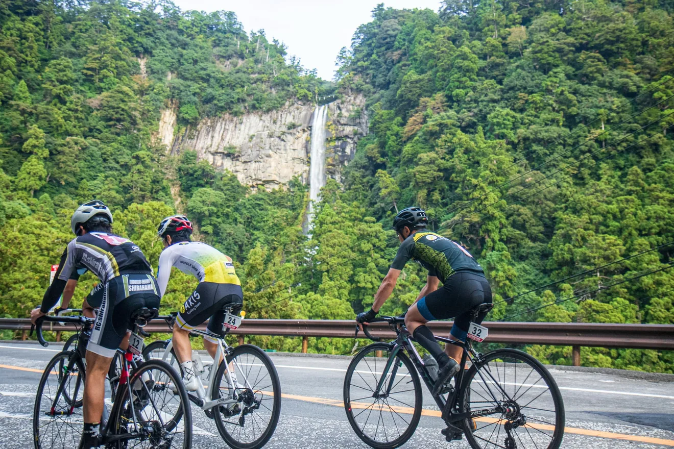 熊野古道ヒルクライムの那智の滝を背に走る参加者（公式参考写真）