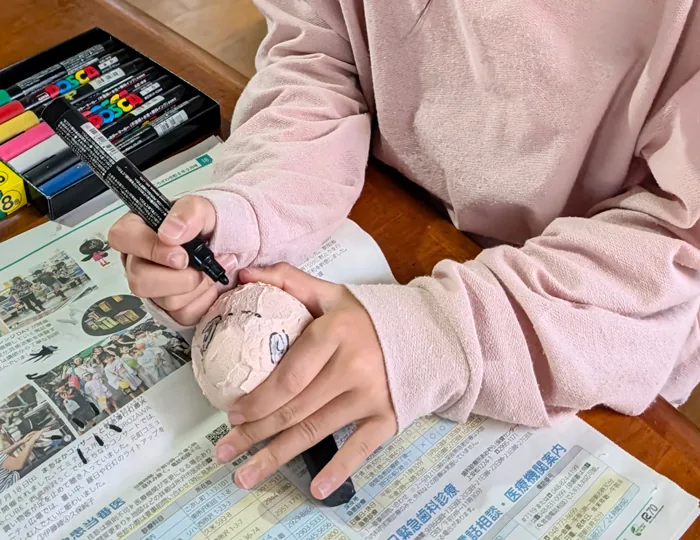 主催の工作教室の案内に掲載された起き上がり小法師の絵付けの参考写真