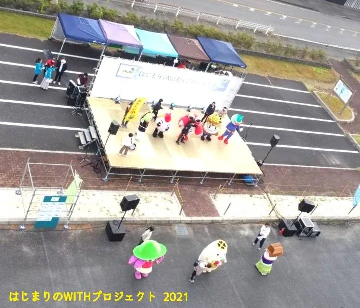 主催者が2026年の紹介に使う、はじまりのWITHプロジェクト2021の過去開催写真。屋外ステージに出演者や着ぐるみが集まる場面。